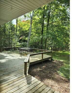Enjoy a serene forest view from this elevated deck with a bench and table.