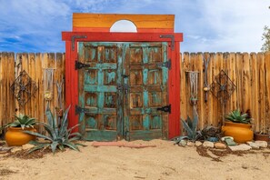 A rustic wooden fence with a large, weathered door in the center. - Valley of the Palms House (Twentynine Palms)