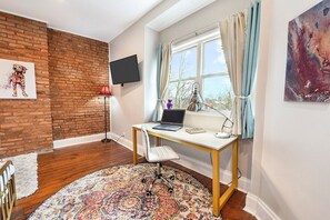 Guest room with a brick accent wall, large window, and modern desk setup.