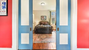 A bedroom with a bed, a window, and a door leading to another room. - Pet-Friendly Home w/ Fire Pit, Mexican War Streets. Walk to PNC Park! (Pittsburgh)