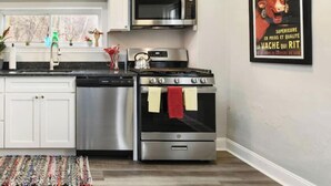 A modern kitchen with white cabinets, stainless steel appliances, a microwave, an oven, and a sink. - Pet-Friendly Home w/ Fire Pit, Mexican War Streets. Walk to PNC Park! (Pittsburgh)