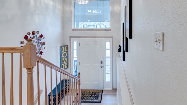 Un escalier avec une rampe en bois menant à une porte blanche sur laquelle est apposée une plaque indiquant « DOMICILE ».