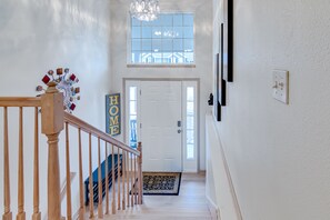 A staircase with a wooden handrail leading to a white door with a 'HOME' sign. - Spacious duplex home in St. Joseph, MO (Saint Joseph)