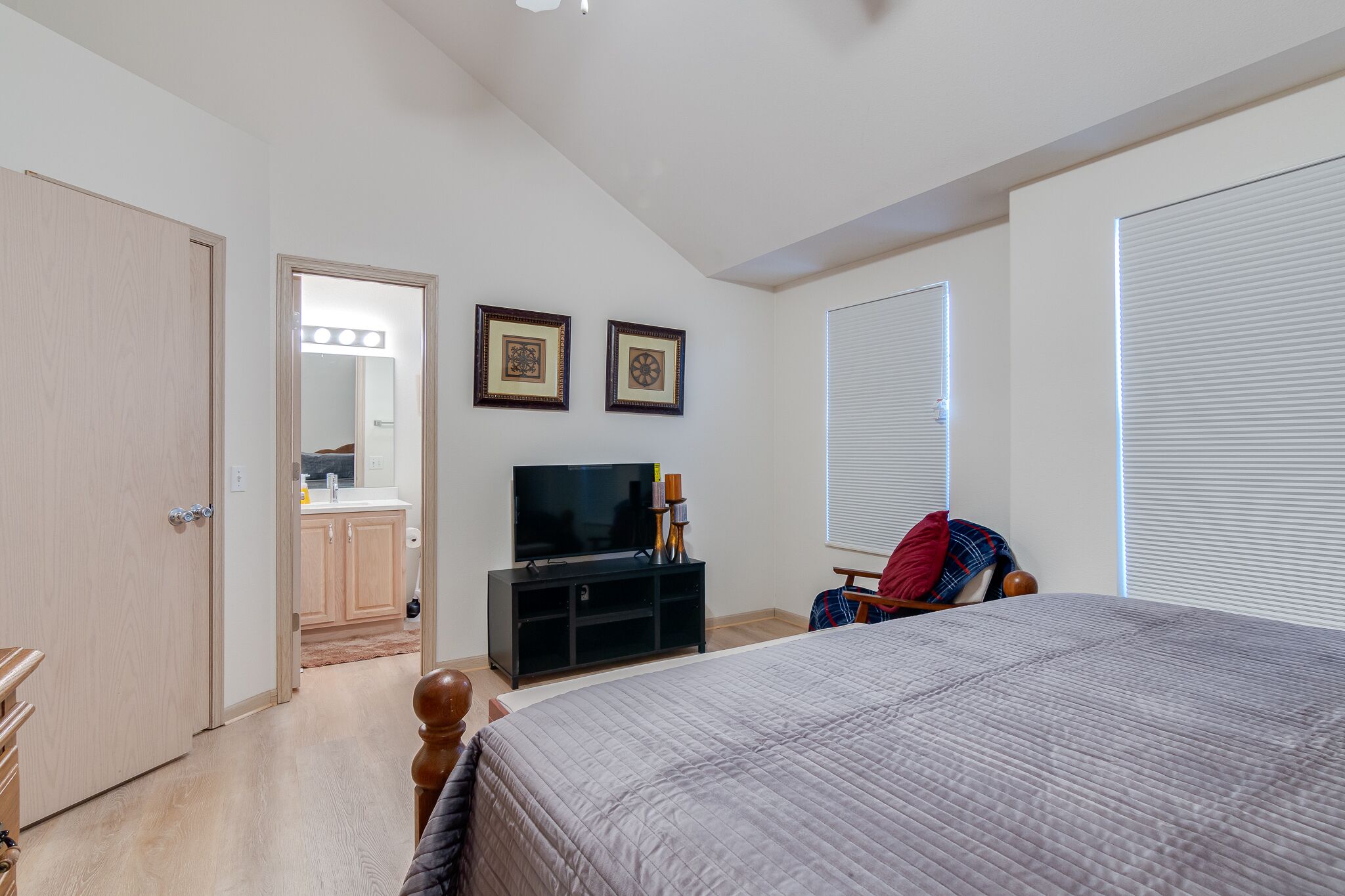 Una camera da letto con un letto, una TV, un armadio e un bagno con uno specchio e luci.