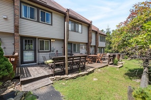 Une maison à deux étages dotée d’un patio aménagé avec du mobilier d’extérieur.