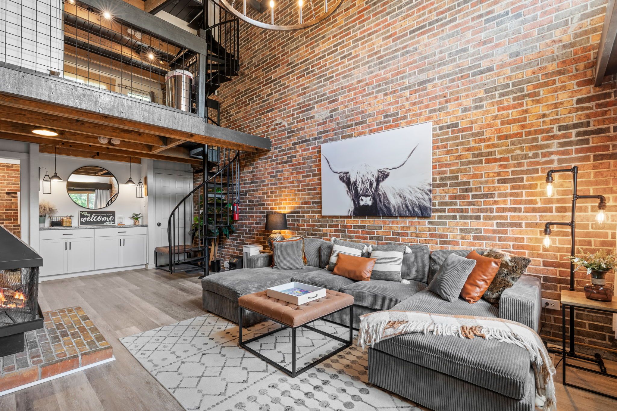 A modern living room with a fireplace, a sofa set, and a large brick wall.
