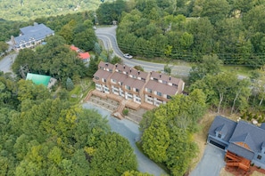 Un immeuble résidentiel à plusieurs étages, doté d’une cour intérieure et entouré d’une forêt dense.