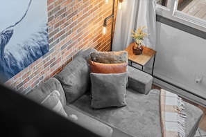 Un salón moderno con un sofá gris, un plaid de piel y una pequeña mesita de madera con un jarrón.