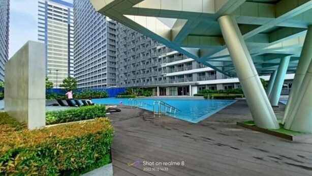 Un edificio moderno con zona de piscina, que incluye una alberca y una terraza.