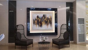 Un vestíbulo con dos sillones negros, una mesa redonda y un cuadro abstracto grande en la pared.