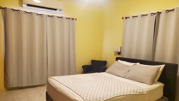 Una camera da letto con un letto, tende, una sedia e un condizionatore d'aria.