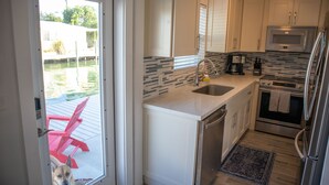 A compact kitchen with white cabinets, a stainless steel refrigerator, a microwave, and a dishwasher. - Oceanside waterfront 2/2 home with 55ft dock and paddle equipment (Marathon)