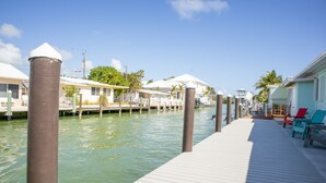A waterfront dock with moored boats, a wooden walkway, and a row of buildings with white roofs. - Oceanside waterfront 2/2 home with 55ft dock and paddle equipment (Marathon)
