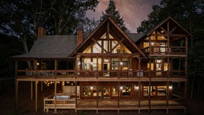A two-story log cabin with multiple balconies and large windows, surrounded by trees. - Blue Ridge Luxury Cabin with Sunset Views (Mineral Bluff)