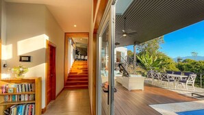 A modern interior with a wooden staircase leading to a balcony with outdoor furniture. - Breathtaking Ocean View Villa, Monkeys Daily, Private Gated Development (Manuel Antonio)
