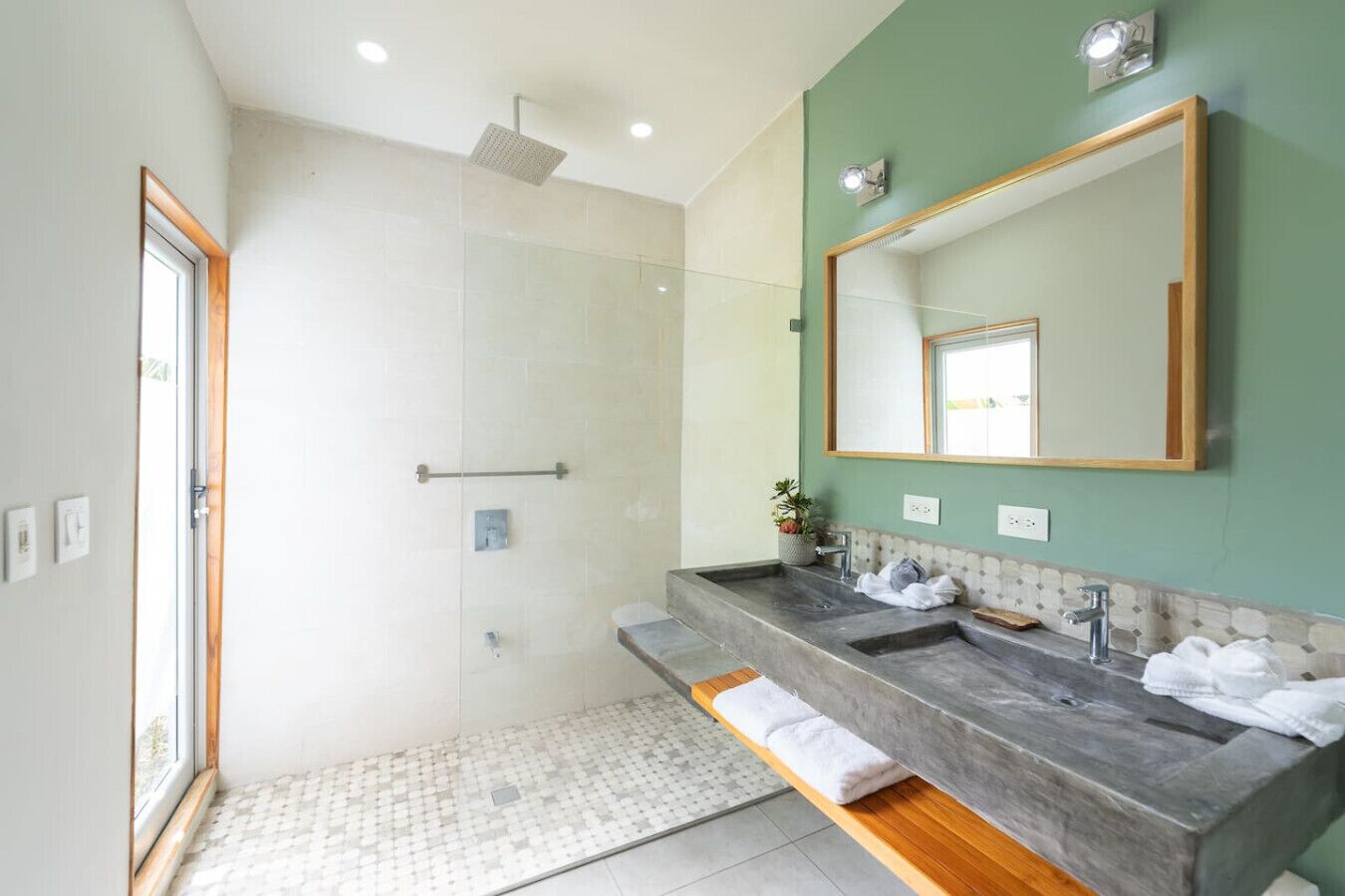 A modern bathroom with a glass shower enclosure, dual sinks, and a large mirror.