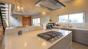 A modern kitchen with a central island, stainless steel appliances, and pendant lighting. - Breathtaking Ocean View Villa, Monkeys Daily, Private Gated Development (Manuel Antonio)