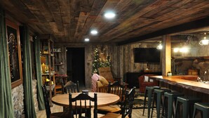A rustic interior with a wooden ceiling, a Christmas tree, a stone wall, and a bar area with stools. - Cozy up in this rustic Stone Lodge and relax by the fireplace (Cleveland)