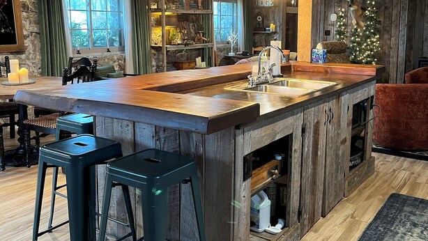 A rustic kitchen with a wooden island, bar stools, and a Christmas tree. - Cozy up in this rustic Stone Lodge and relax by the fireplace (Cleveland)