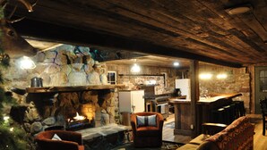 A rustic interior with a stone fireplace, wooden ceiling, and a cozy seating area. - Cozy up in this rustic Stone Lodge and relax by the fireplace (Cleveland)