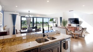 Una cocina moderna con encimeras de granito, doble pileta y un comedor con vistas.