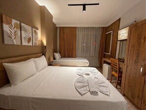 A hotel room with two beds, a TV, a desk, and a wardrobe.