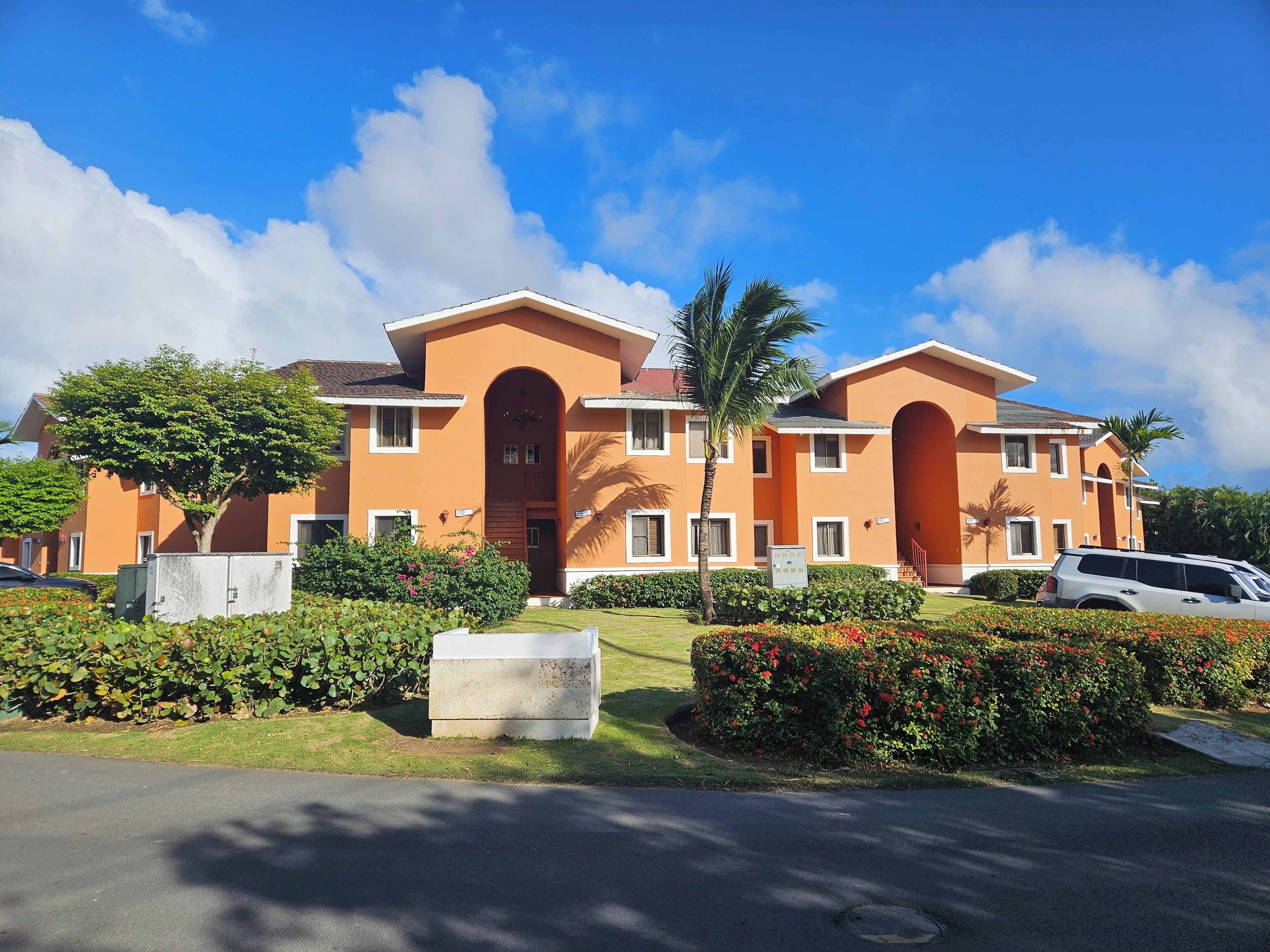 A two-story building with a central entrance, surrounded by well-maintained gardens and a parking area.