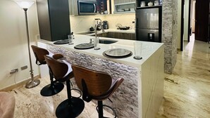 Una cocina moderna con una isla central, taburetes de bar e iluminación colgante.