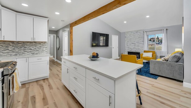 A modern kitchen with white cabinets, a central island, and a stone backsplash. - Open calender. Washer/dryer. Complementary Netflix. Struck Gold (Reno)