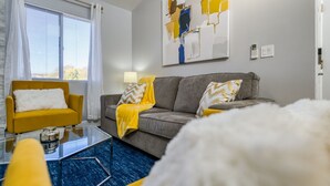 A living room with a sofa, armchair, and a glass coffee table. - Open calender. Washer/dryer. Complementary Netflix. Struck Gold (Reno)