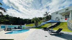 Una piscina con una tumbona y un área de descanso techada.