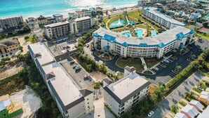 Ett flygbildsfoto av ett hotell med en pool, flera byggnader och en strand i bakgrunden.