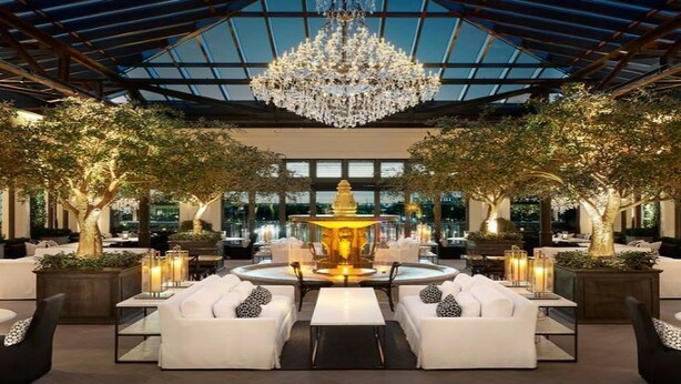 A luxurious indoor setting with a central fountain, white sofas, and a large chandelier.