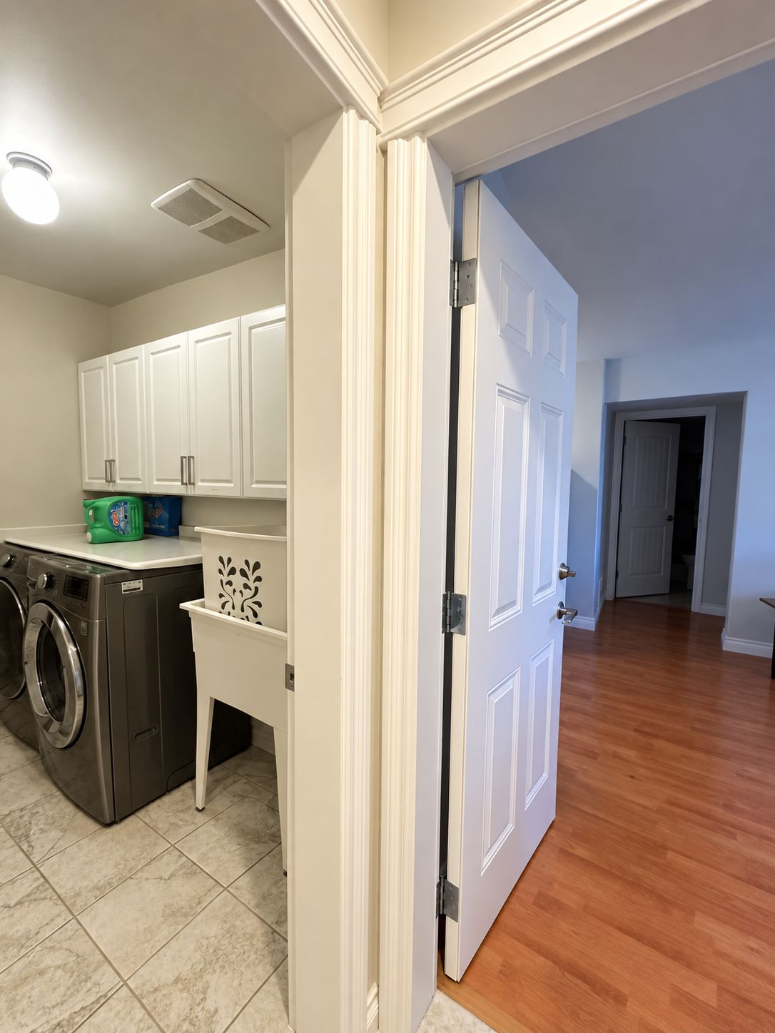 Un espace buanderie comprenant un lave-linge, un sèche-linge et un meuble de rangement.