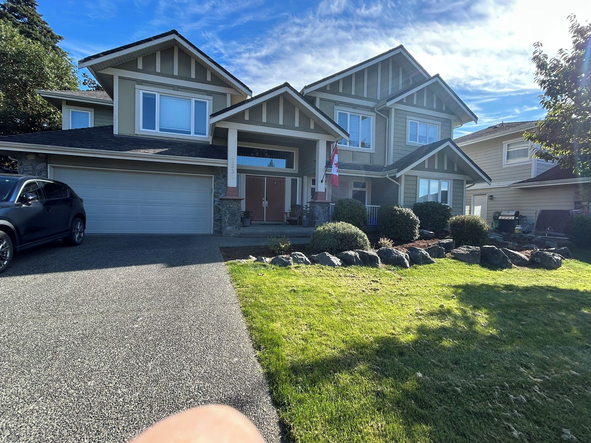 A two-story house with a garage, a driveway, and a well-maintained lawn.