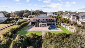 Une grande maison avec une piscine, un patio couvert et une pelouse bien entretenue.