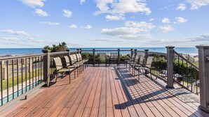 Une terrasse en bois avec des sièges extérieurs et une vue sur l’océan.