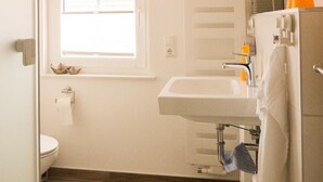 Ein kleines Badezimmer mit Toilette, Waschbecken, Fenster und einer kleinen Treppe.