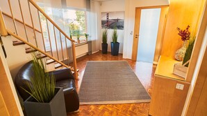 Een modern interieur met een houten vloer, een zwarte leren bank, een trap met houten leuningen en een groot raam met uitzicht op een brug.