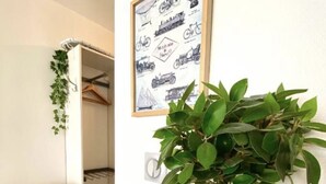 Ein Zimmer mit einer Topfpflanze, einem gerahmten Bild an der Wand, einem Sessel und einem Holztisch.