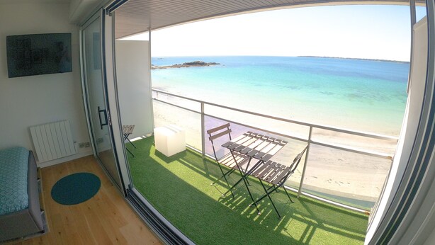 Ein Balkon mit Meerblick, einem kleinen Tisch und einem Stuhl.