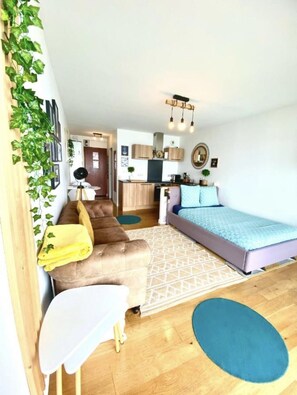 A compact living space with a sofa, a bed, a small table, and a kitchen area.