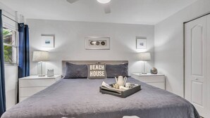 Quarto com cama grande, duas mesas de cabeceira com luminárias, cabeceira e luminária fixada na parede.