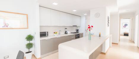 Une cuisine moderne avec des meubles blancs, un îlot central et une petite plante en pot.