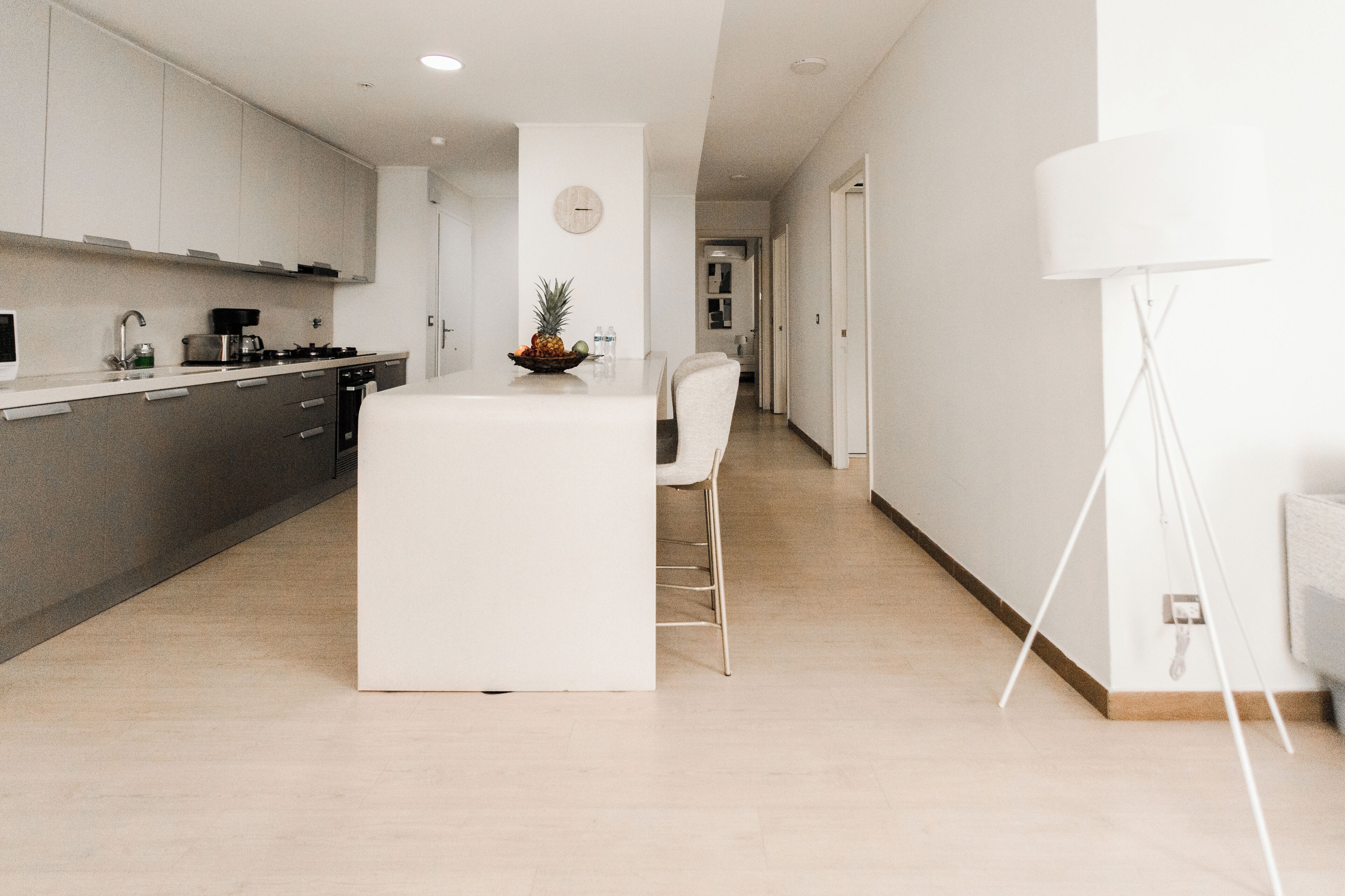 A modern kitchen with a central island, a dining area with a white table and chairs, and a minimalist design.