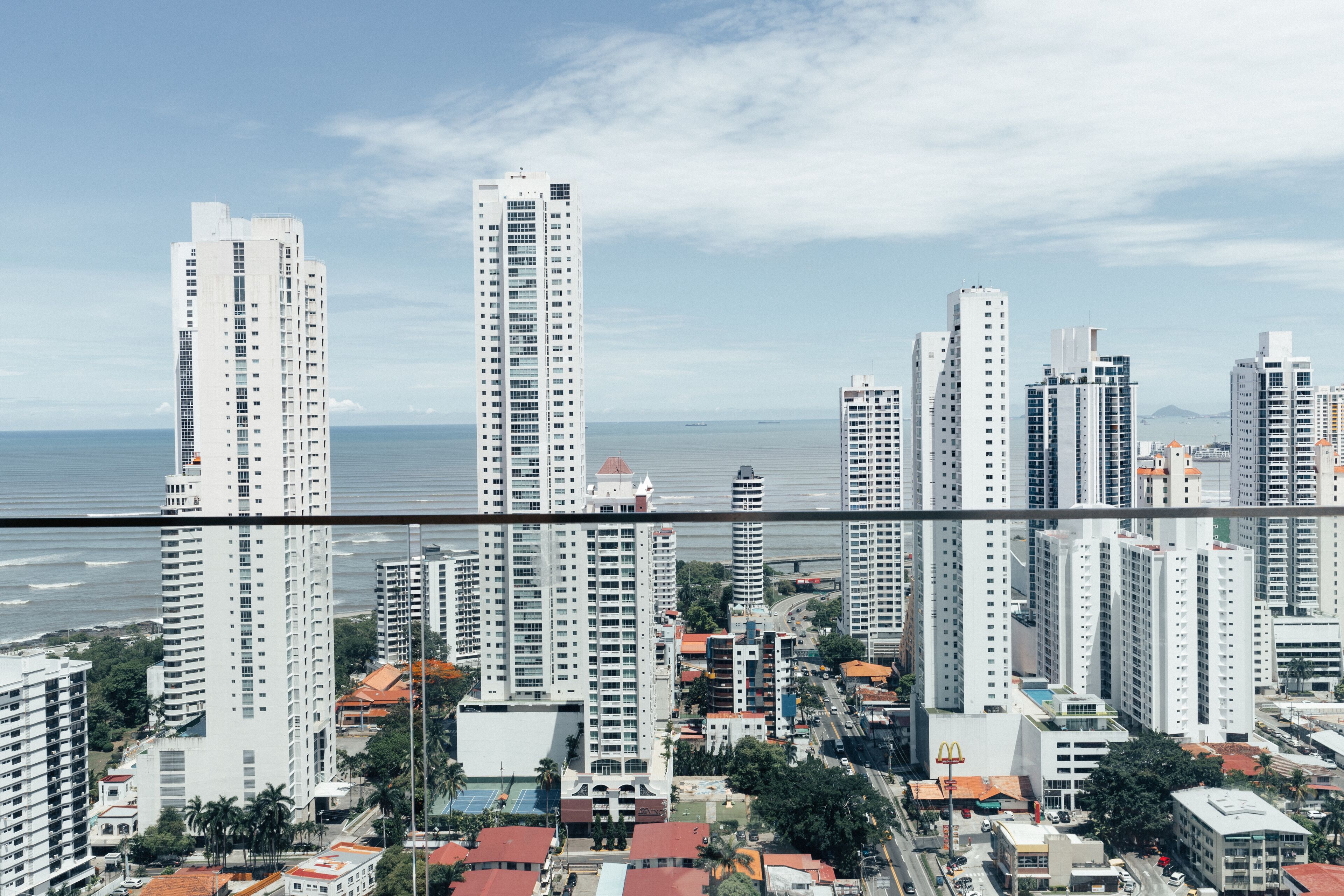 Un edificio alto con varios pisos, vista al océano y edificios urbanos circundantes.