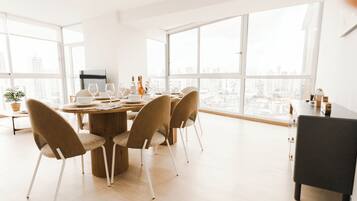 Un comedor moderno con una mesa redonda, cuatro sillas y vistas a la ciudad a través de amplias ventanas.