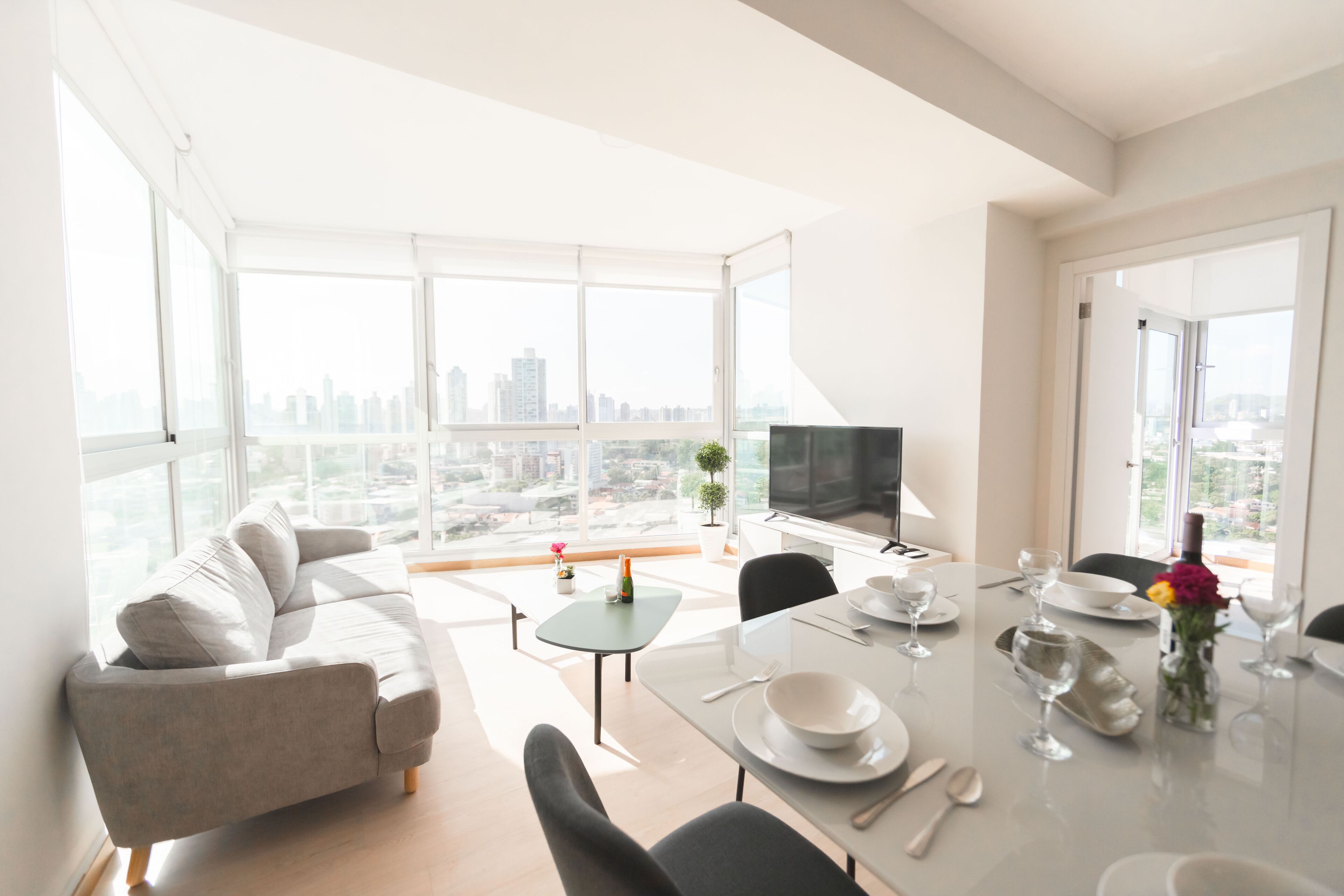 A modern living room with a sofa, dining table, and city view.