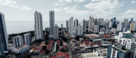 A cityscape with high-rise buildings, a busy street, and a body of water in the background.