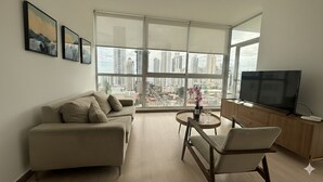 A modern living room with a sofa, a TV, and a dining area with a table and chairs. - Boutique Apartments Panamá Coco del Mar (Panama City)